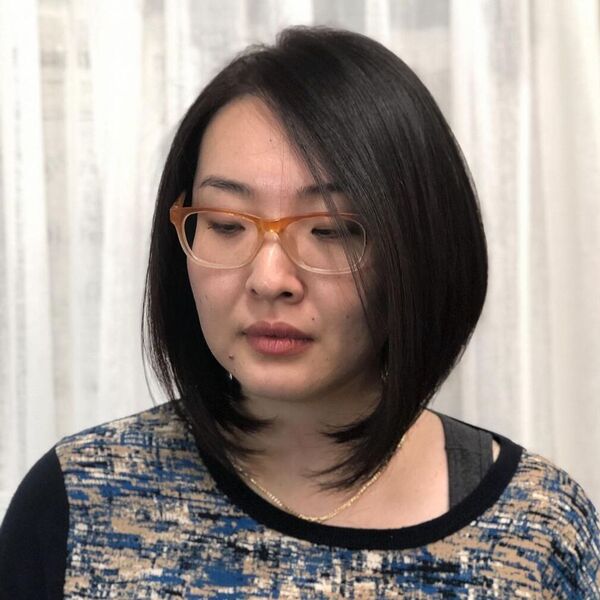 Shiny Side Parted Bob - a woman wearing glasses in black printed top.