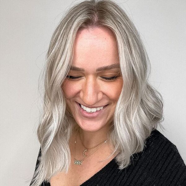 Wavy Platinum Blonde - a woman wearing knitted black top.